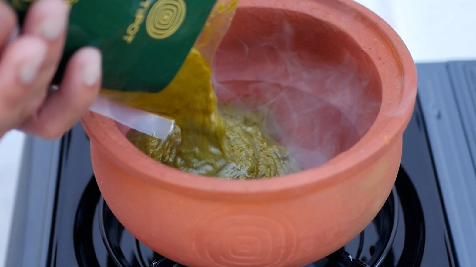 A Spinach Saag Base pouch poured into the Mitipot on the stove